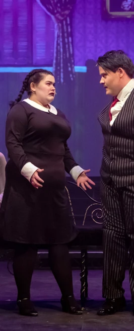 Dramatic scene with actors in gothic-themed costumes, having a serious conversation on stage, surrounded by ghostly figures. Dramatic scene with actors in gothic-themed costumes, having a serious conversation on stage, surrounded by ghostly figures.